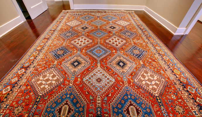 a clean antique rug with an intricate design, laid out on a wooden floor