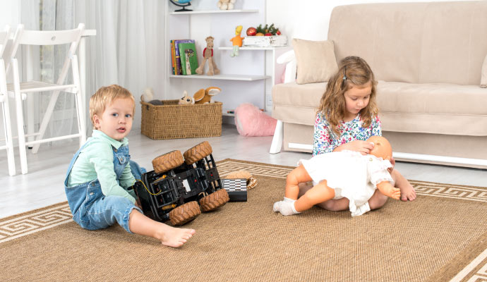 Children playing with toys on a clean rug in living room